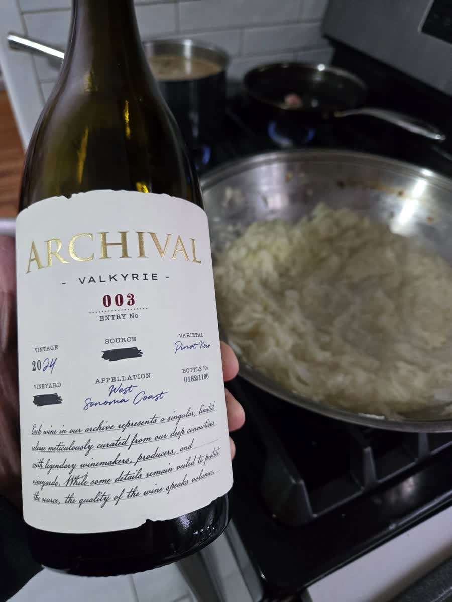 A bottle of Valkyrie, Entry No. 003, held up in a kitchen mid-cook